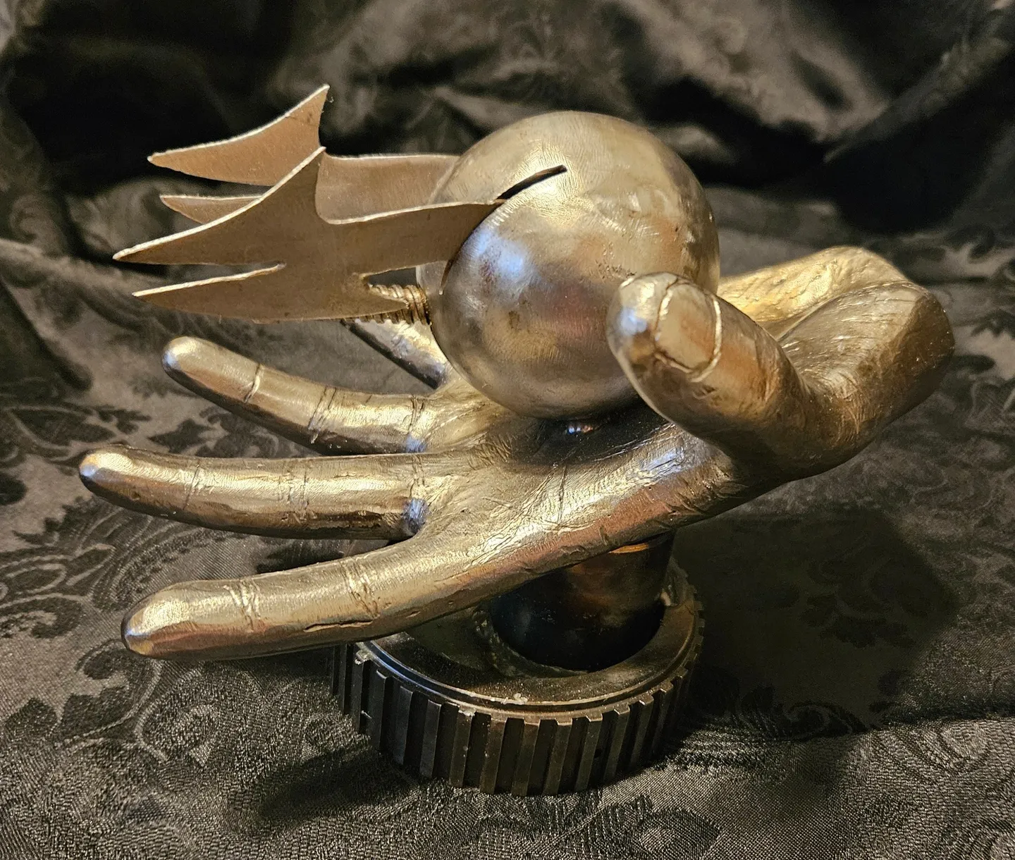 A gold sculpture of hands holding an object.