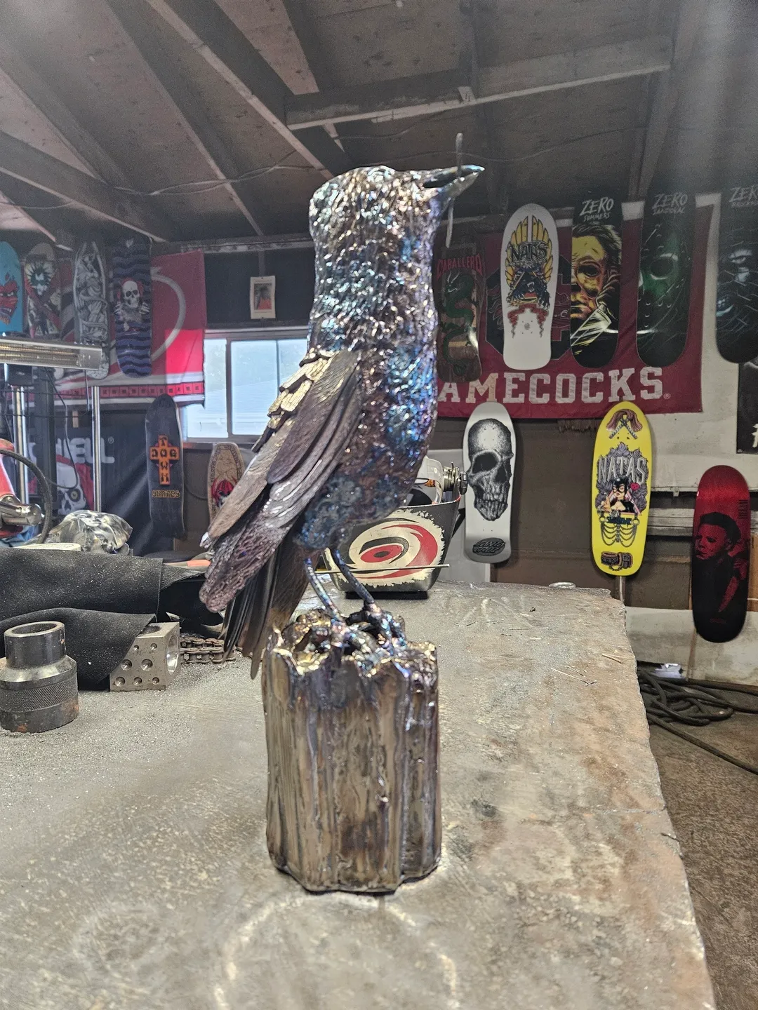 A bird statue sitting on top of a wooden stump.