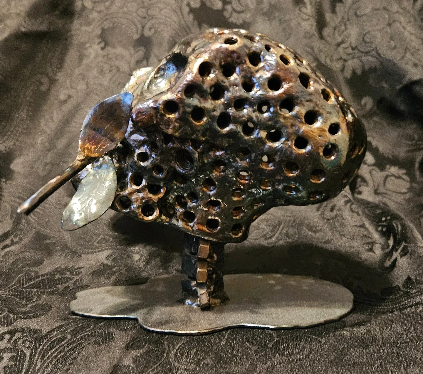 A metal sculpture of an elephant with holes in it.