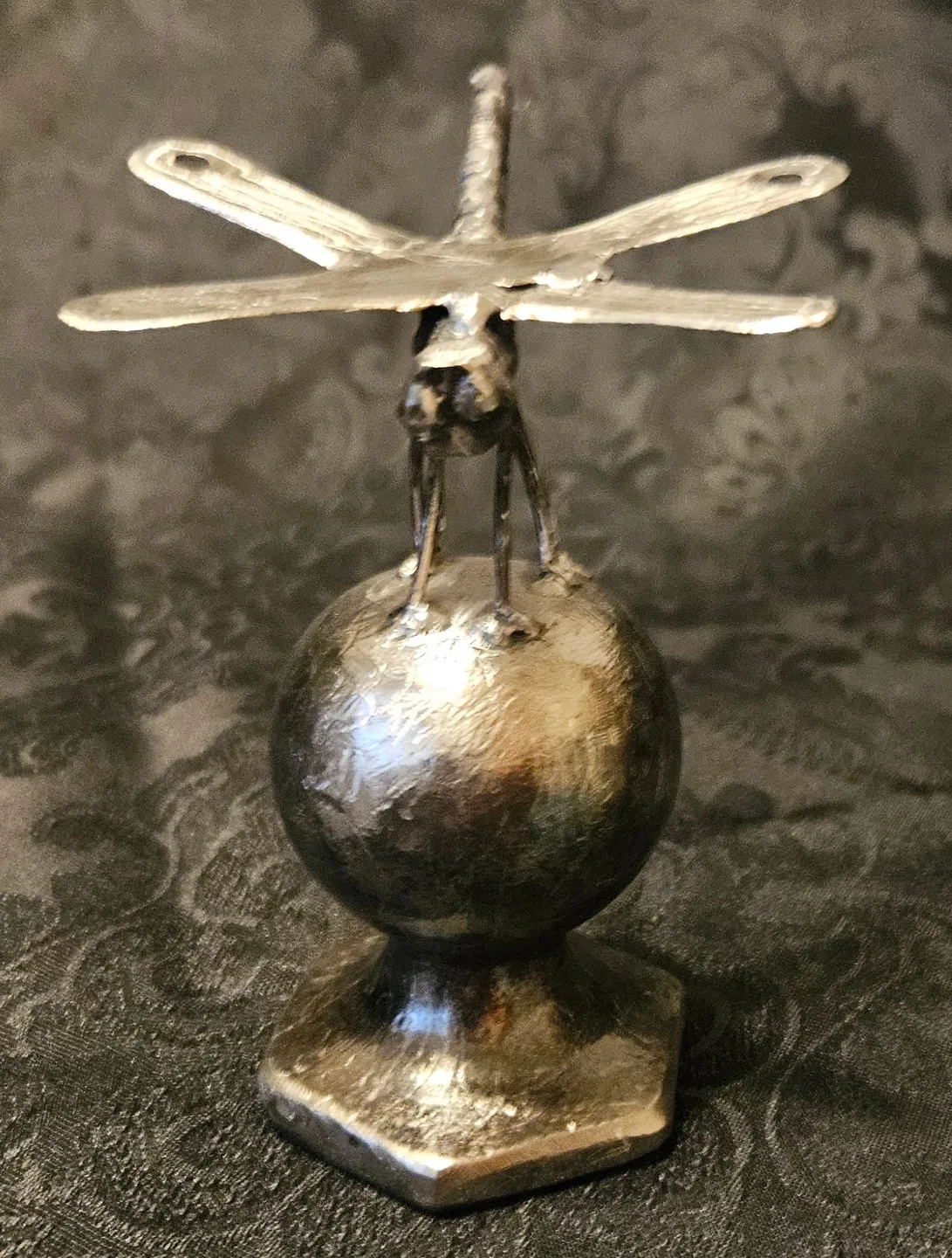 A metal sculpture of an airplane on top of a ball.