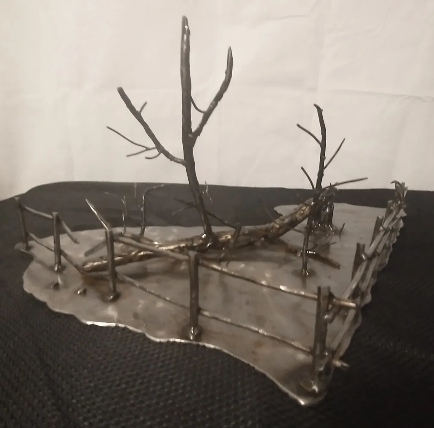 A metal sculpture of trees and branches on top of a table.