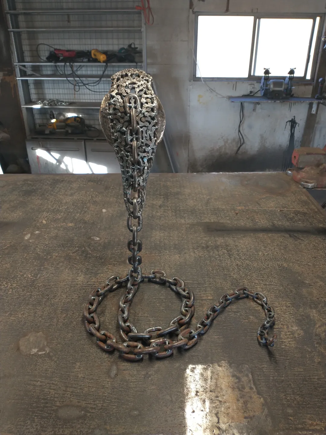 A chain is curled around the base of a sculpture.