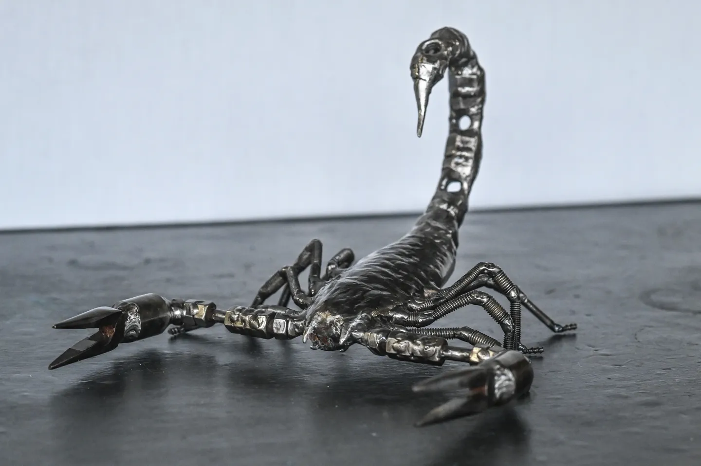 A metal sculpture of an animal sitting on the ground.