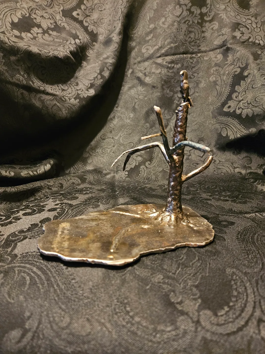 A bronze sculpture of a tree on top of a leaf.