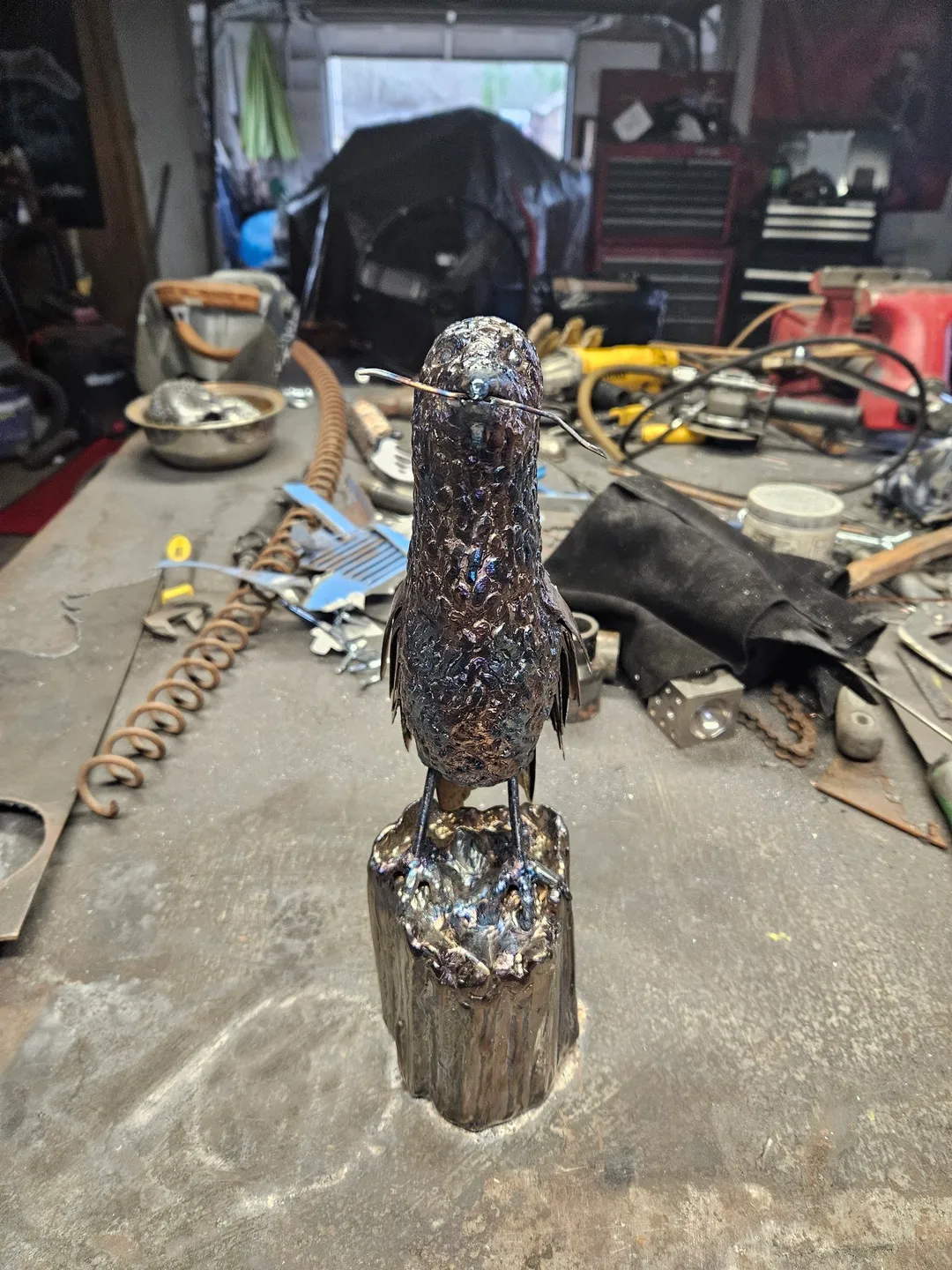 A bird statue sitting on top of a wooden stump.