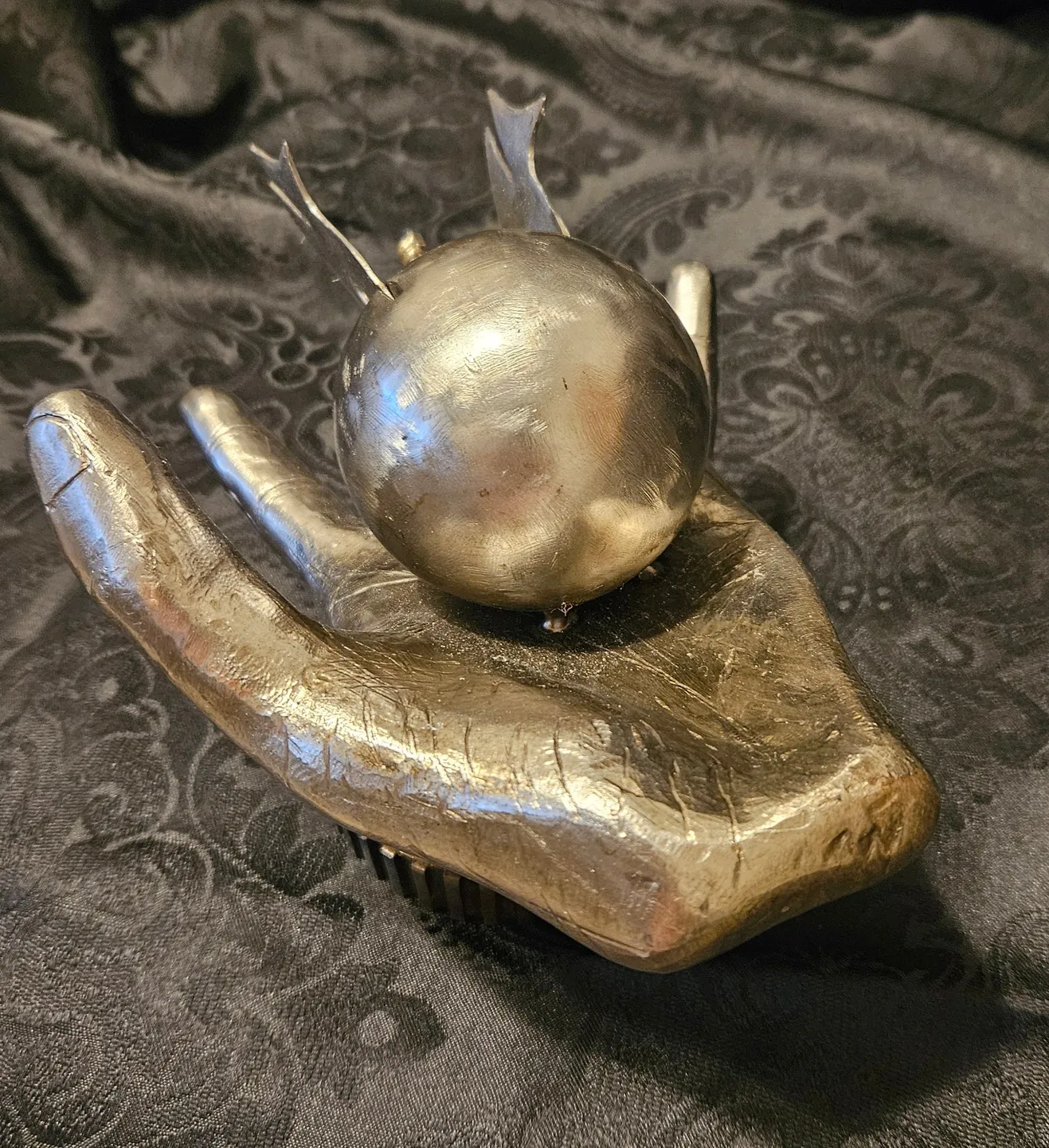 A hand holding an object with a ball on top of it.