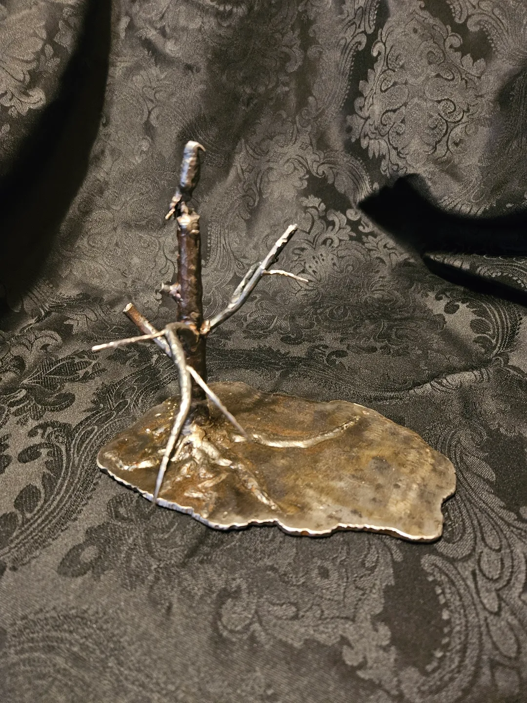 A metal sculpture of branches on top of a leaf.