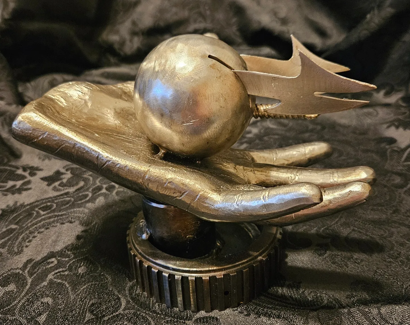 A metal sculpture of a hand holding a ball.