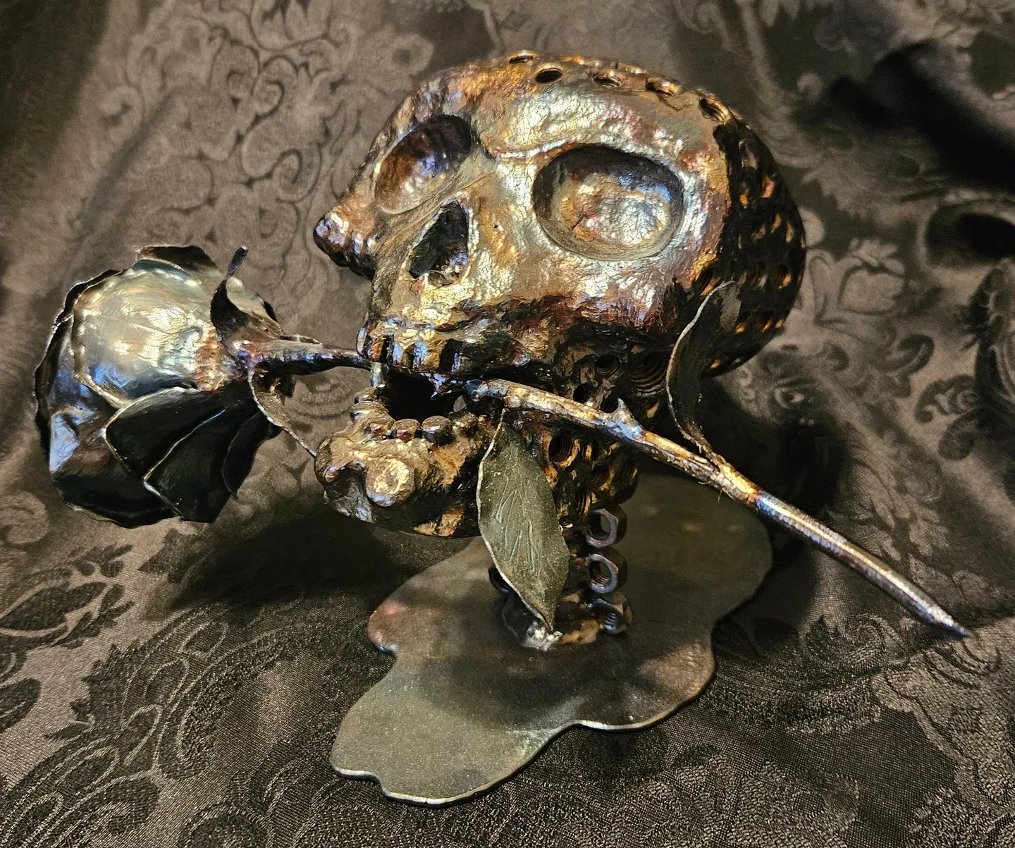 A metal skull with a rose in its mouth.