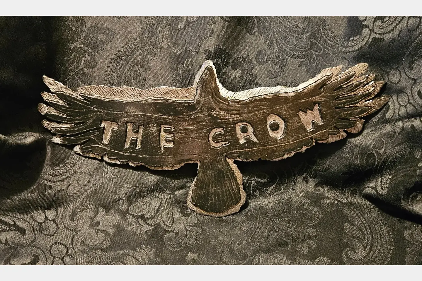 A wooden bird with the word " the crow " written on it.