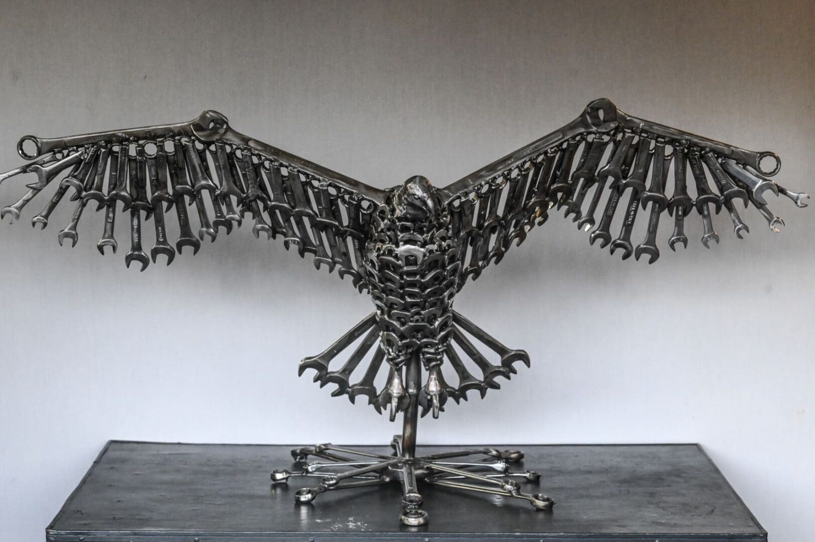 A metal sculpture of an owl made out of wrenches.