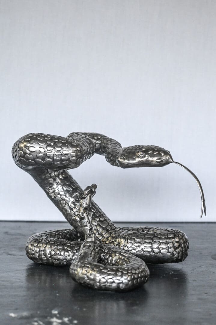 A silver snake sculpture sitting on top of a table.