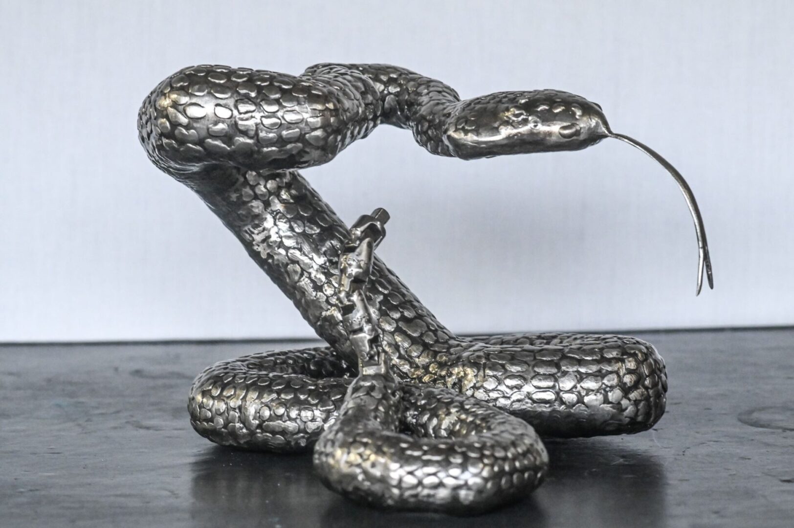 A silver snake sculpture sitting on top of a table.