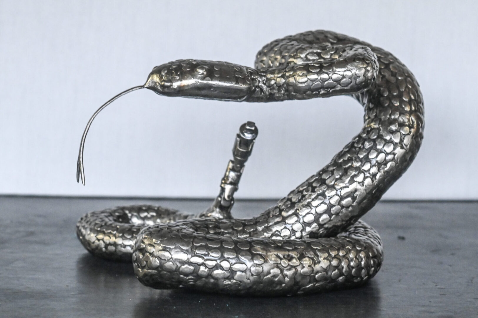 A silver snake sculpture with a white background