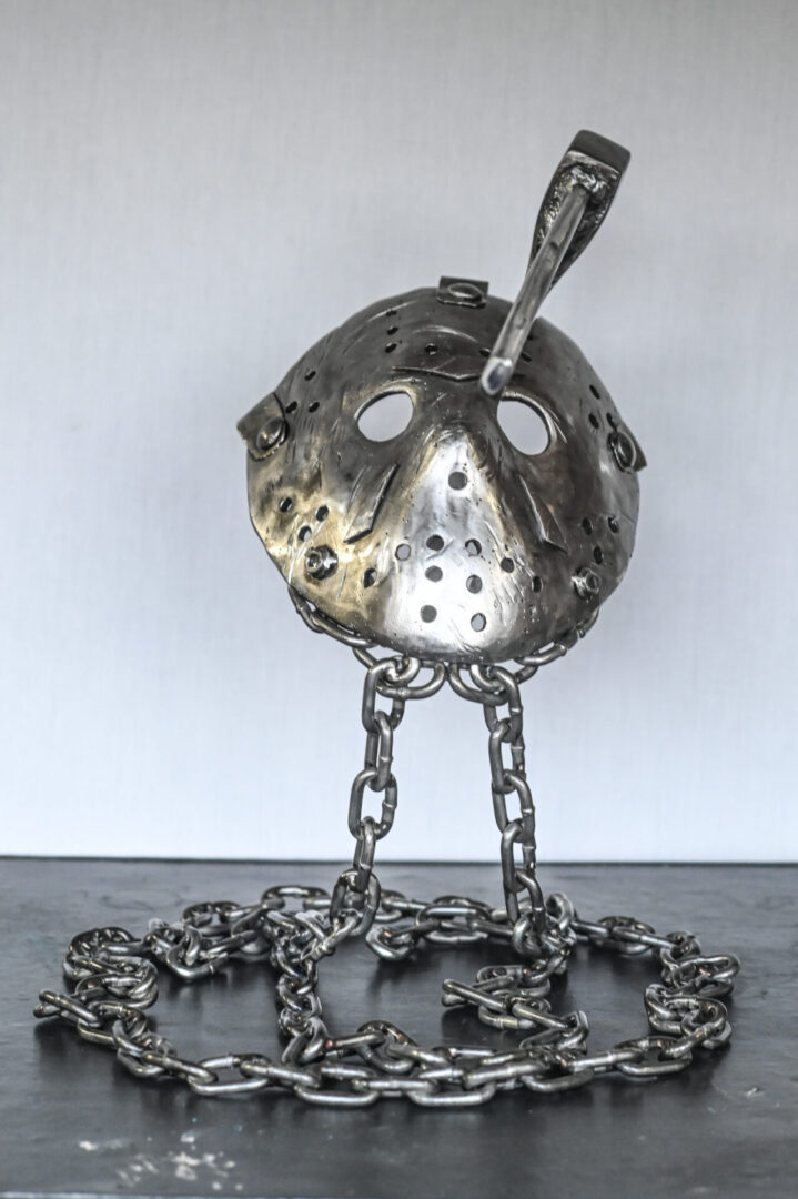 A metal sculpture of a hockey mask on chains.