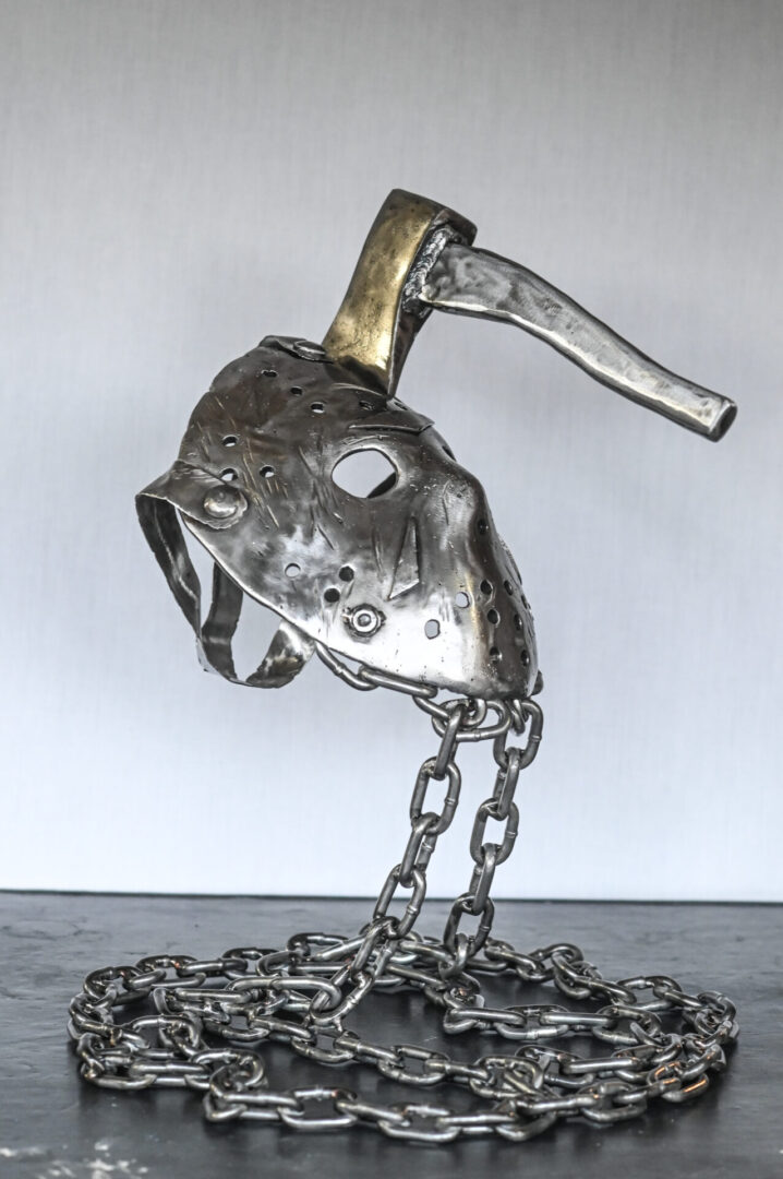 A metal sculpture of a hockey mask and chain.