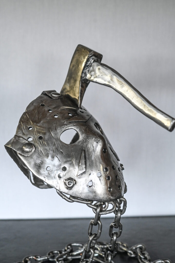 A metal mask with an axe hanging from the side.