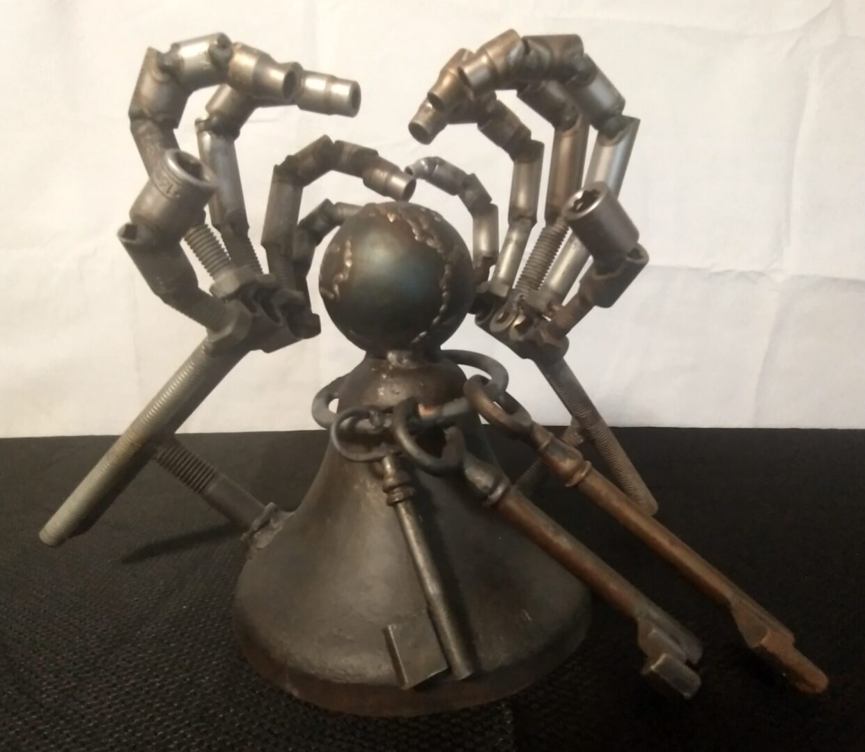 A metal sculpture of a spider and hands.