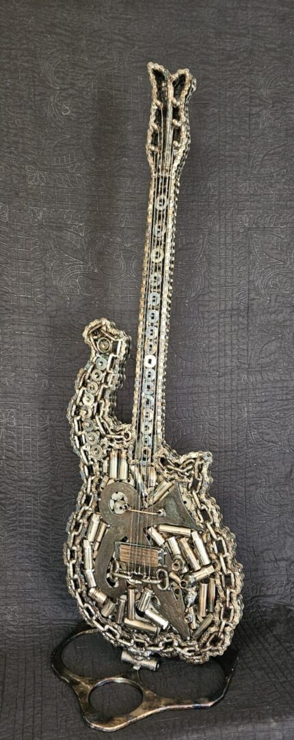 Metal sculpture of a guitar on a stand.